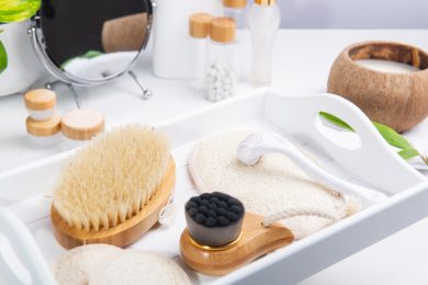 Dry lymphatic drainage massage wooden brushes, derma mezoroller and loofah pads for face and body skin care on a white tray. Bathroom treatments. Homemade care. Natural beauty and zero waste concept